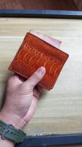 The wallet is made of ostrich leather in tamarind brown color.