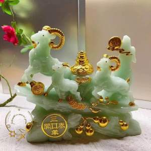 Green jade three goats with golden accents on a decorative base.