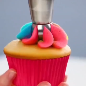 Stainless steel piping tips for cake decorating with three different nozzle designs creating pink green and mint green frosting patterns.