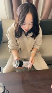 Glass Tea Infuser Cup for Tea Separation with Black Lid and Strap Pouring Tea into Glass Jar.