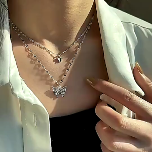 gold-plated/Silver layered necklace with butterfly pendant and small charm. Sparkling stones on butterfly. Delicate chain design. Suitable for casual or formal wear. Ideal for everyday or special occasions.