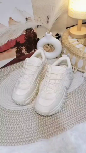 White sneakers with thick soles and textured design. Casual footwear