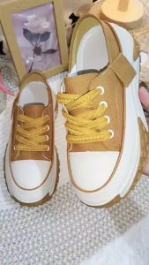 Brown and white platform sneakers with yellow laces and textured soles. Casual footwear for everyday wear.