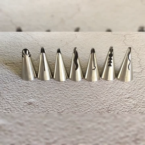 Stainless steel piping tips for cake decorating with 8 different nozzle designs. Cupcakes with colorful floral icing and a decorated cake with flowers.