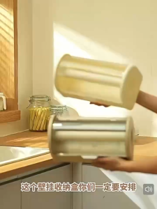 Anti-dust kitchen paper towel storage box with two compartments for paper towels and plastic wrap mounted on a refrigerator.