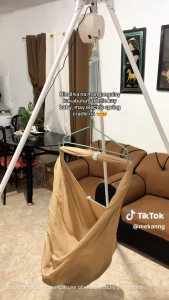 Baby swing with 7 strong springs for ultimate safety holds up to 19kg. Blue mesh design. Hanging from white stand. In nursery with wooden crib and framed art.