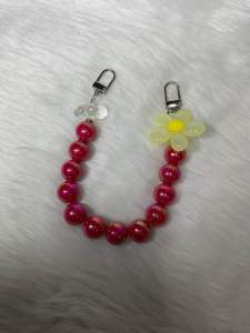 Purple and red beaded tumbler straps with flower and heart charms black and purple loops metal clasps.