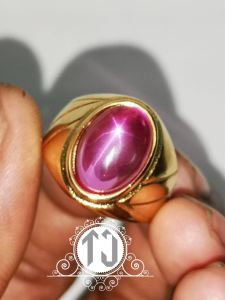 Cincin MERAH SIAM ROSE STAR BANGKOK dengan batu permata merah muda berkilauan di tengah bingkai emas mengkilap cocok untuk acara formal.