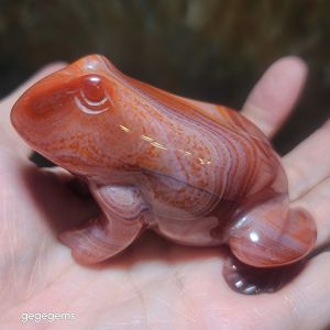Agate frog figurine with striped patterns and glossy finish. Handheld decorative item.