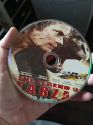 The Legend of Tarzan DVD. Key attributes: movie title Tarzan character DVD format. Fit/use: home entertainment. Scene: hand holding the disc.