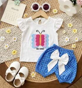 Setelan kupu kupu polka baby perempuan dengan atasan putih bermotif kupu kupu dan celana pendek  bermotif polka dot dilengkapi aksesori bando pita kepala putih
