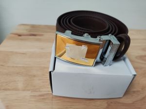 Dây Thắt Lưng Cấp T. Á C A Mẫu Mới Nhất - Dây da màu nâu khóa kim loại màu vàng đặt trên hộp trắng.