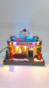 ONELINE #FC820  An LED-lighted Christmas village ice cream shop tabletop decoration featuring a large rotating ice cream cone on the roof and warm glowing interior lights.