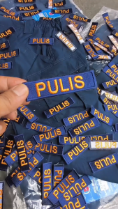 "PULIS" Blue embroidered patches Logo with orange texton a wooden surface.