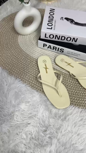 White black brown rose gold flip flops with gold logo on footbed.