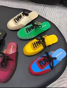 A two-tone half-slipper with a toe cap is worn over a flat lazy one-legged lace-up sporty sandal and slipper