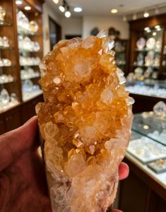 Amber quartz cluster with natural base for display in jewelry store setting.