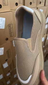 Beige slip-on sneakers with mesh upper and white accents. Casual footwear for everyday wear.