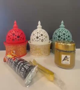 beautifully crafted ceramic incense burner designed for the traditional practice of burning bakhoor and charcoal. The main burner is a red ceramic piece with intricate cut-out patterns and gold detailing adding a touch of elegance to its design.