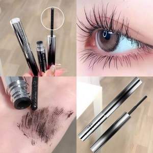 Black mascara with silver tube and brush. Thick dark pigment. Long curled lashes. Close-up of eye and hand.