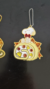 Snoopy on top of a Swiss roll cake hanging enamel decoration