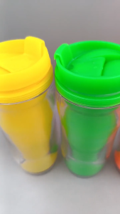 Four colorful travel tumblers with lids. Transparent body spill-proof design portable size. Suitable for on-the-go use.