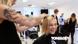 TONI&GUY ผ้าคลูมช่างตัดผม กันเปื้อน ขนาด 71 x 54 ซม. ผ้าร่มกันน้ำได้ สายคล้องคอไคว้หลังยาว 75 ซม. ตะเข็บแน่น กระดูมล็อค กระเป๋าหน้า 3 ช่อง - สีดำ