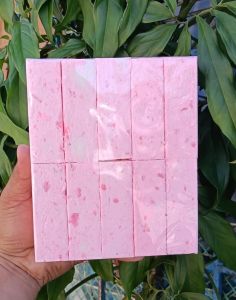 Niacinamide Pink Soap 1kilo - Pink soap with speckles - Handheld for personal use - Natural setting with green leaves.
