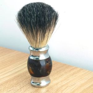 แปรงโกนหนวดแบดเจอร์ที่ทําด้วยมือสีน้ําตาลพร้อมที่จับโลหะ เครื่องมือร้านทําผมมืออาชีพหรูหราสําหรับบุรุษสําหรับการดูแลผิวหน้า