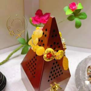 Yellow Beaded Bracelet with Flower Charm on Wooden Stand with Floral Background