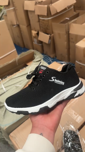 Black mesh sneakers Breathable lace-up closure cushioned heel lightweight casual wear. Outdoor setting.