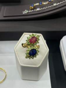 แหวนเงิน 925 ประดับด้วยพลอยน้ำเงินและทับทิมเจียระไนทรงวงรี ล้อมรอบด้วยพลอยซาโวไลท์และพลอยบุษราคัม