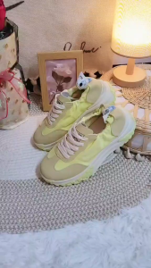 Beige and yellow sneakers with white laces and textured soles. Casual footwear for everyday wear.