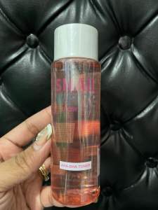 SNAIL WHITE GLOW AHA-BHA Toner 150ml - Clear bottle with pink liquid white cap label on front held in hand against black tufted background.