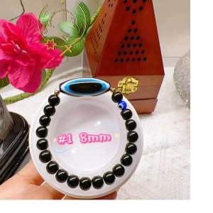 Black beaded bracelet with blue evil eye charm.