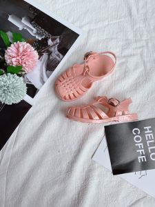 รองเท้าแตะรัดส้นสีลูกกวาดสไตล์โรมันสำหรับเด็กนักเรียนประถมแบบใหม่ฤดูร้อนรองเท้าแตะรัดส้นปิดหัวปิดฉลุลายแบบมีสายรัดสำหรับเดินชายหาดแช่แข็ง