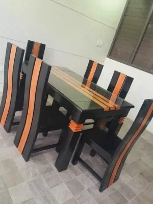 Black and orange dining table set with glass top and six matching chairs.