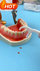 White dental floss for cleaning between teeth. Fits use in oral hygiene routine. Scene: close-up of person using flosser. 50pcs