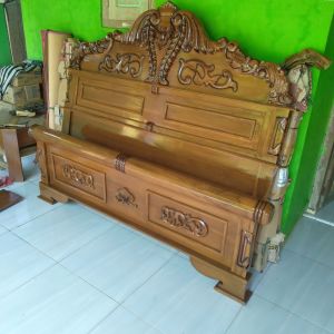 Tempat tidur ranjang peluru kayu ukiran dengan kepala tempat tidur tinggi dan kaki tempat tidur kokoh.