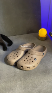 White Crocs-style slide sandal with adjustable strap and ventilation holes. Casual footwear for indoor or outdoor use.