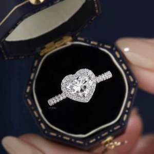 แหวนเพชรโมอีสหญิงรูปหัวใจ หน้าเพชรล้อม บ่าข้างฝังเพชรแถว ตัวเรือนเงินแท้ชุบทองคำขาว พร้อมใบเซอร์