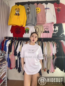 TIPIDSHOP black graphic t-shirt for men and women with "WRK HRD" text made of thick cotton hanging on wooden hanger against brick wall.