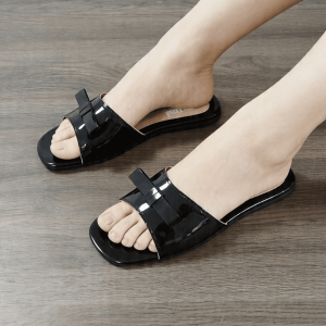 White slide sandals with bow detail flat sole open toe casual wear wooden floor setting