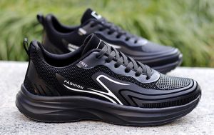 Black athletic sneakers with mesh upper and white accents. Suitable for casual wear and light exercise. Displayed outdoors on a metal surface.