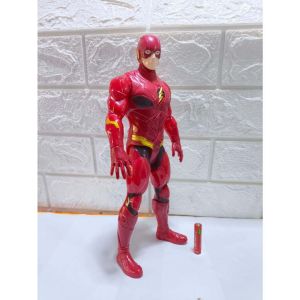 The Flash action figure with yellow lightning bolt emblem and red and yellow accents standing upright on a white surface with a small red cylindrical object nearby.