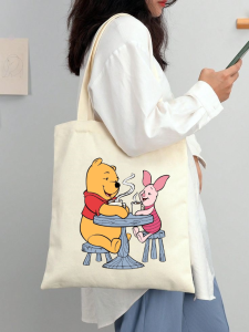 Canvas tote bag featuring Winnie the Pooh Tigger Eeyore and Piglet characters. Casual everyday use. Indoor setting.