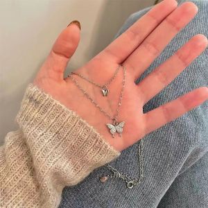 gold-plated/Silver layered necklace with butterfly pendant and small charm. Sparkling stones on butterfly. Delicate chain design. Suitable for casual or formal wear. Ideal for everyday or special occasions.