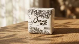Orange Maze Serviette 100g box with value pack 6 in 1. Black and white leaf pattern design. Natural light on wooden surface.