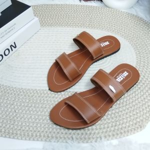 Brown and black two-strap flat sandals with beige option. Brown stitching on straps. Metal stud detail on black strap. Flat sole. Casual wear. Displayed on textured surface.
