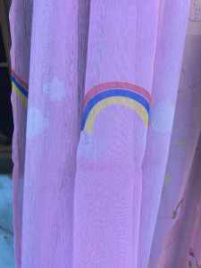 rainbow sheer curtain with rainbow and cloud patterns. Suitable for childrens room or playful decor.
